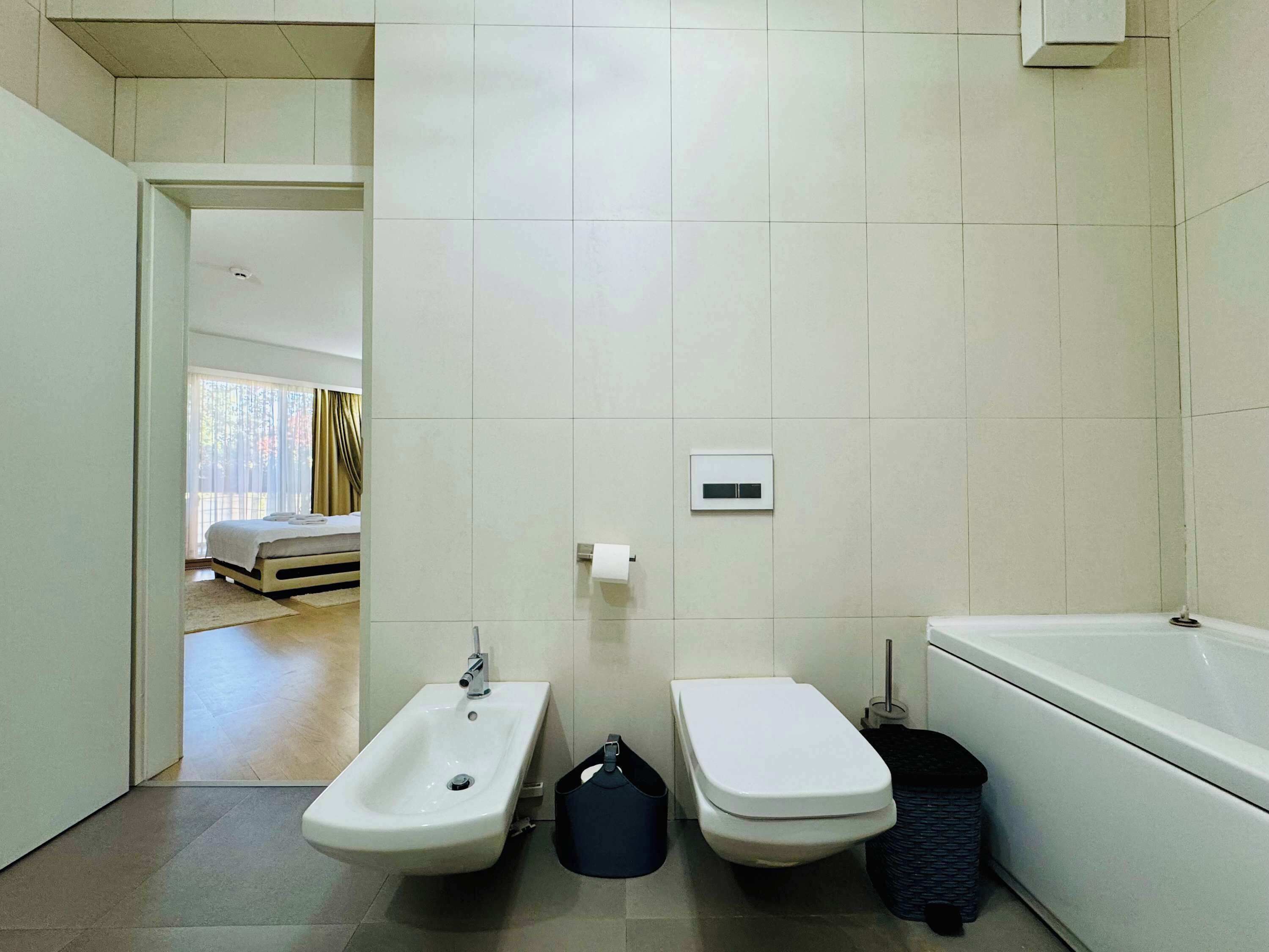 A modern bathroom with a bidet, toilet, and bathtub.