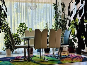 Een eetgedeelte met een tafel, stoelen en plantenpotten.