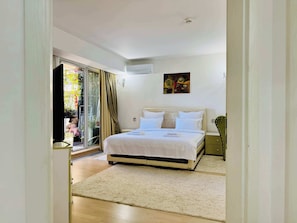 Een slaapkamer met een bed, een schuifdeur naar een balkon en een schilderij aan de muur.
