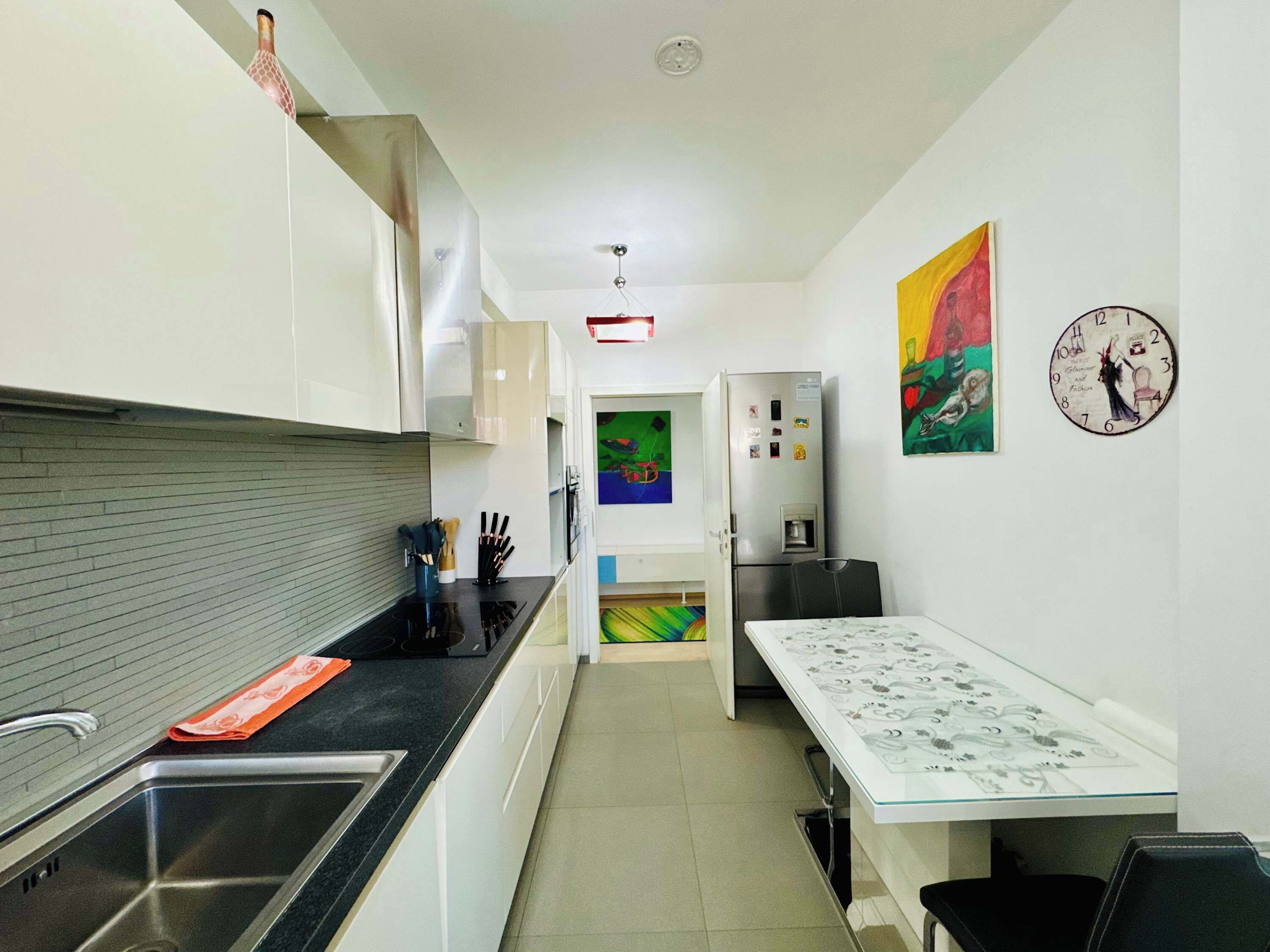 Eine moderne Küche mit Spüle aus Edelstahl, einem Kühlschrank und einem Essbereich mit Tisch und Stühlen.