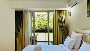 A hotel room with a bed, curtains, an air conditioning unit, and a view of greenery outside. - Joy City Stay - Memorandului (Timișoara)