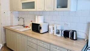A kitchen with white cabinets, a sink, a microwave, a coffee maker, and a toaster. - Joy City Stay Family Ultracentral (Timișoara)
