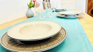 Ein Esstisch gedeckt mit Tellern, Gläsern und einer Blumenvase.
