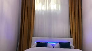 Un llit amb un edredó blau, almoines blanques i un capçal amb il·luminació blava.