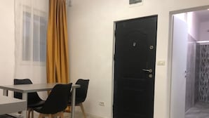 Una habitació amb una taula de menjador, cadires, una porta negra i una cortina groga.