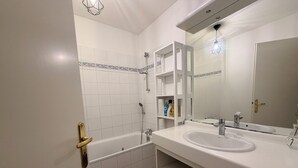 Un bany amb banyera, un lavabo, un mirall i una dutxa.