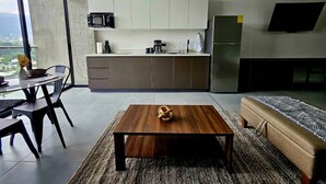 Ett modernt kök med vita skåp, en matplats med bord och stolar samt ett vardagsrum med en soffa och ett soffbord.