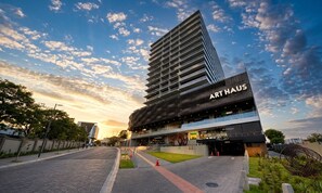 A modern building with a prominent 'ART HAUS' sign, featuring a glass facade and a rooftop terrace. - Studio Apartment in San Benito, with balcony & volcano views. (San Salvador)