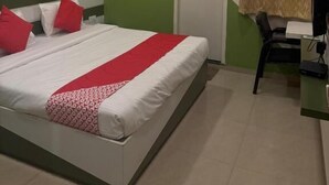 A bedroom with a bed, a desk, a chair, an air conditioner, and a door. - Hotel SR (Sanwer)