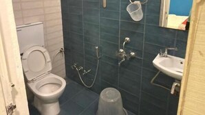 A bathroom with a toilet, shower, and sink. - Hotel SR (Sanwer)