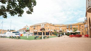 A courtyard with a paved area, benches, and outdoor seating. - Cozy 1BR Seaside Apt in Brighton Marina Village (Brighton and Hove)