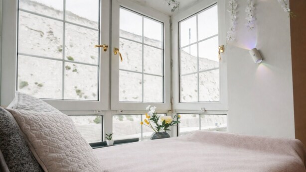 A bedroom with a bed, a window with a view of a snowy landscape, and a small plant on the windowsill. - Cozy 1BR Seaside Apt in Brighton Marina Village (Brighton and Hove)