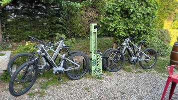 Two bicycles parked on a gravel path with a green post nearby.