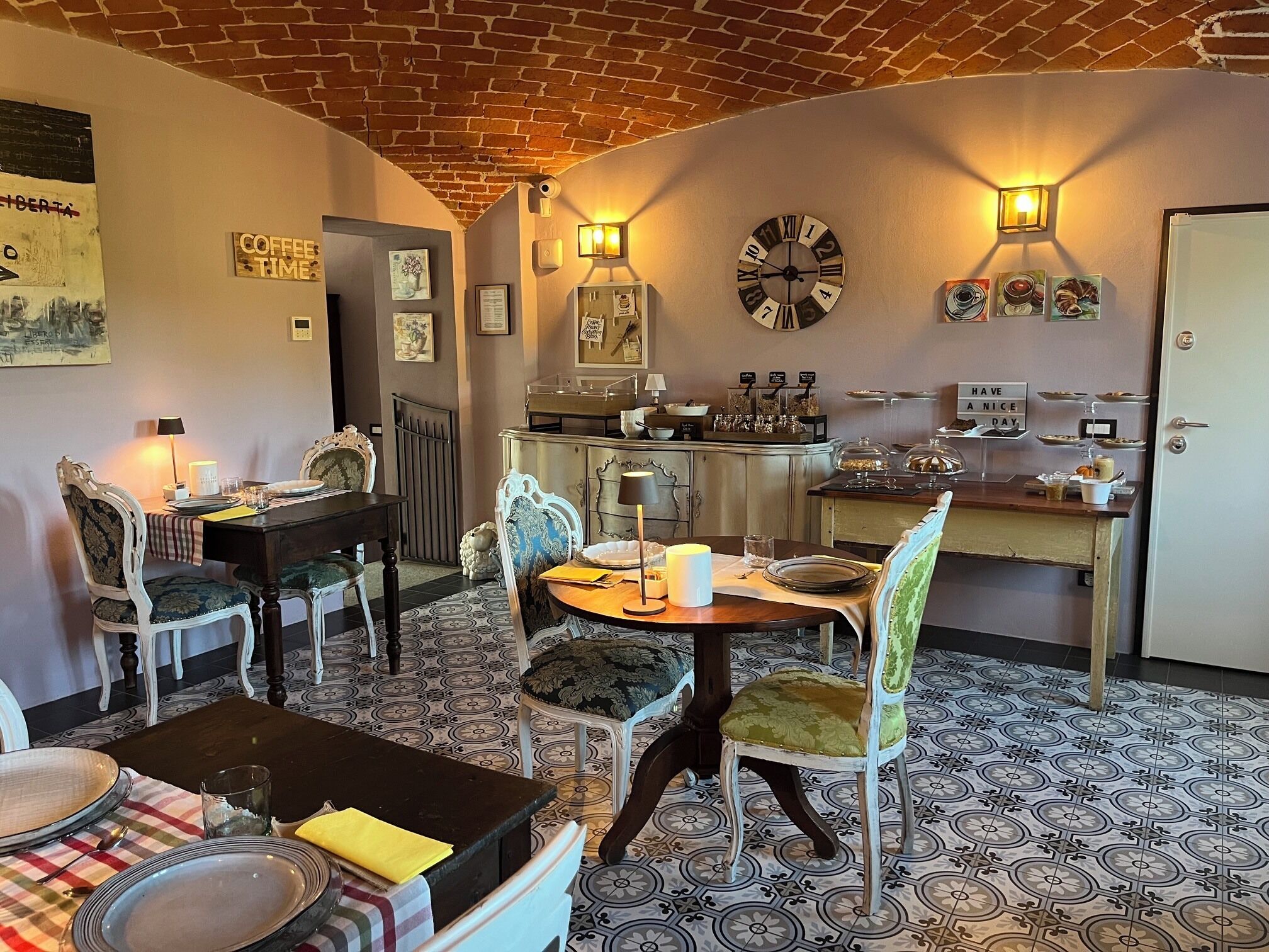 Un comedor con techo de ladrillo, un reloj, luces empotradas en la pared y una zona de cocina con estación de café.