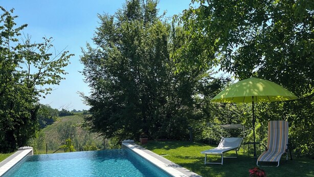 A swimming pool with a clear blue water surface, surrounded by lush greenery and trees. - Noi Due B&B nel Monferrato (Quargnento)