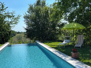 Una piscina al aire libre de temporada, sombrillas