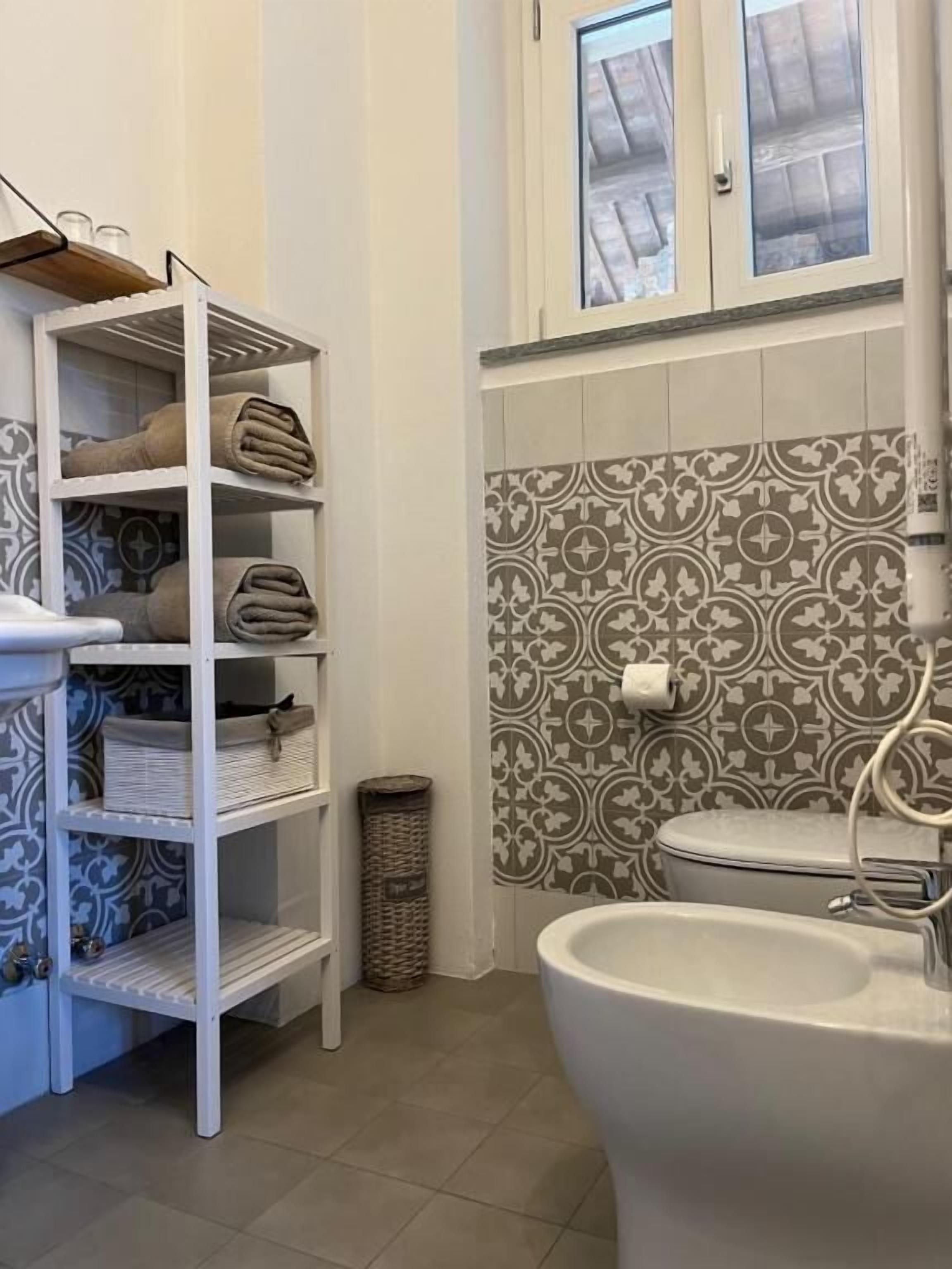 A bathroom with a white sink, a toilet, and a shelf with towels.