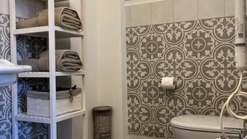 A bathroom with a white sink, a toilet, and a shelf with towels.