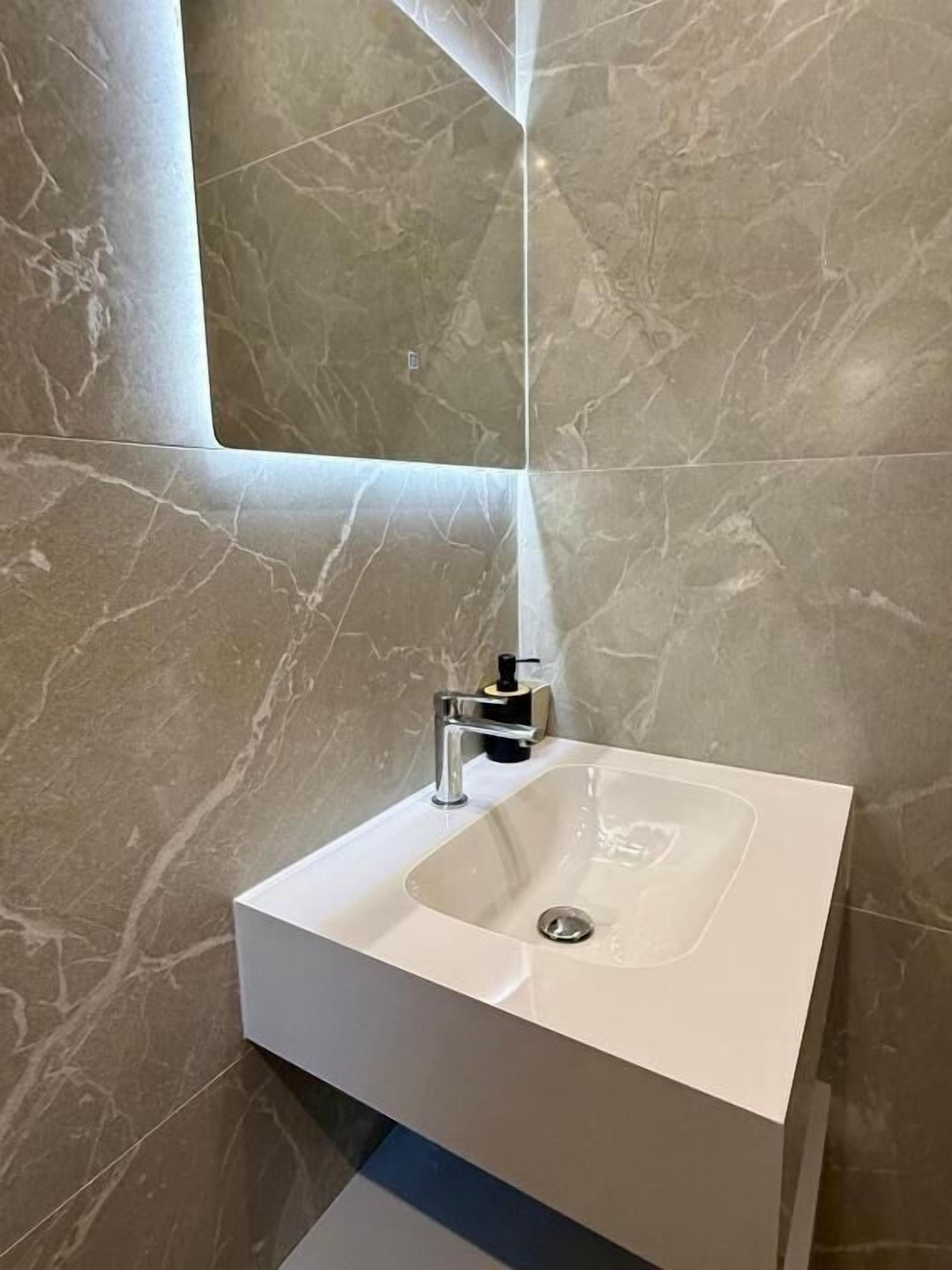 A bathroom with a white sink, a mirror, and a wall with a marble pattern.