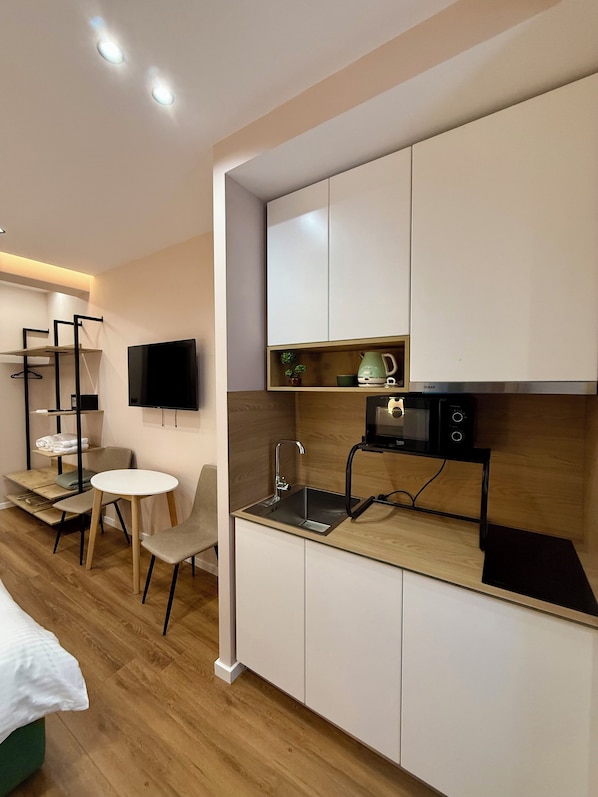 Una cocina moderna con microondas integrado, un lavamanos y una pequeña zona de comedor con mesa y sillas.