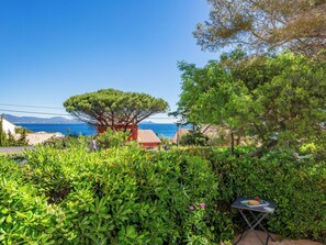 Ein Garten mit einem Tisch, einem Baum und Blick aufs Meer.