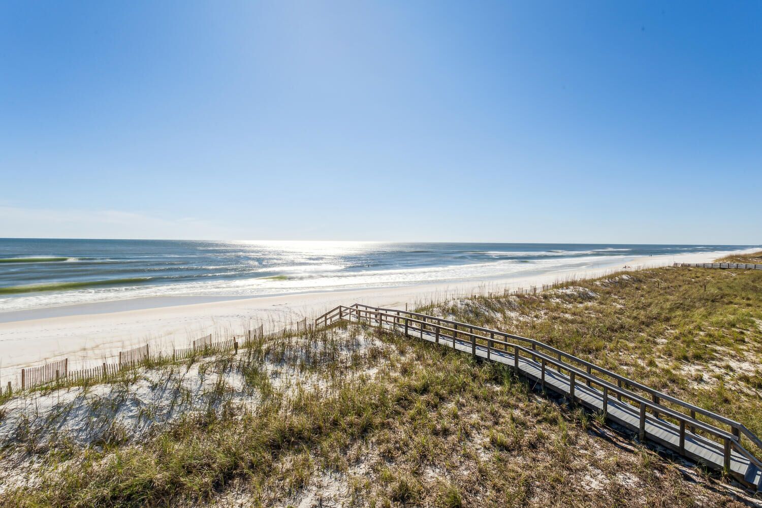 Ein Strand mit einer Holzpromenade, die zum Ufer führt.