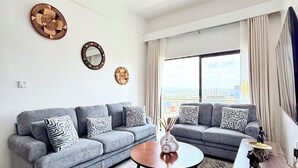 Una sala moderna con un sofá seccional gris, una mesa de centro redonda y una alfombra estampada.