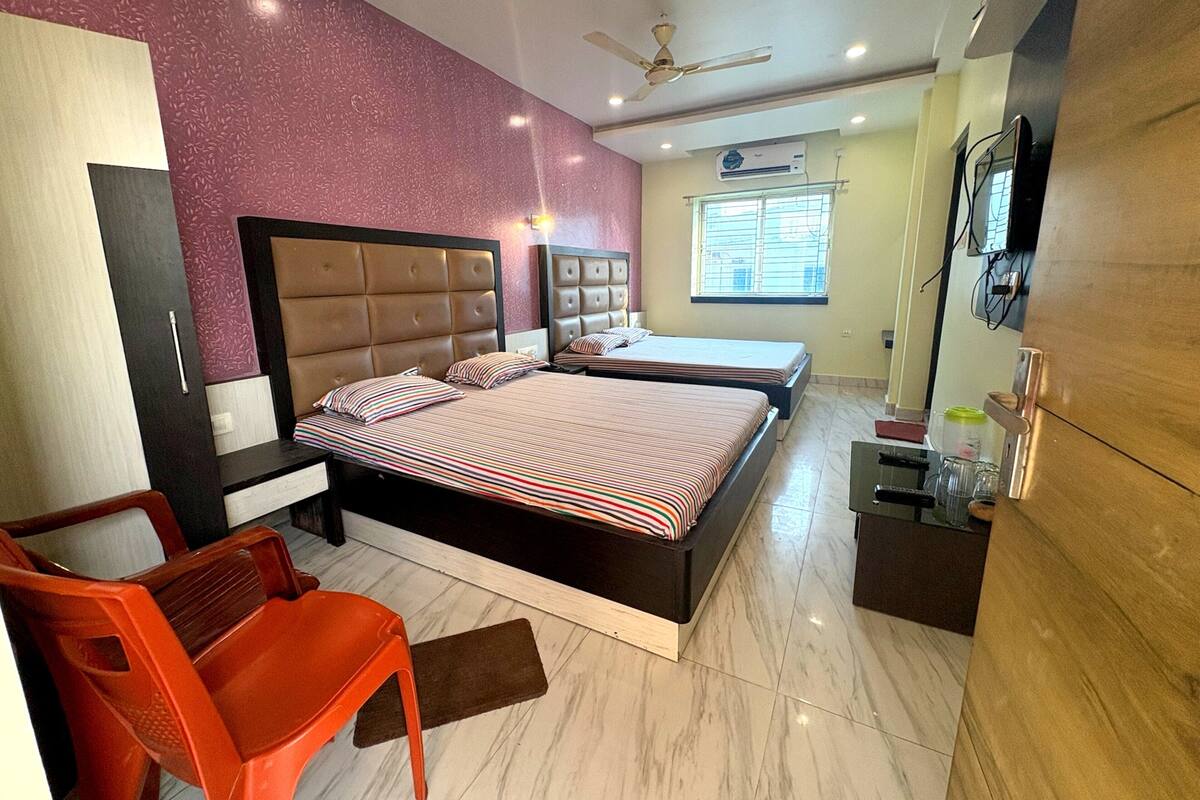 A bedroom with a bed, a chair, a wardrobe, a television, and a window.