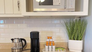 Une cuisine équipée d’un four à micro-ondes, d’une machine à café et d’une plante posée sur le plan de travail.