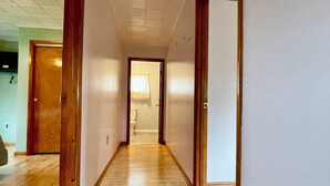 Un couloir doté d’un plancher en bois, de murs blancs et d’un plafond équipé d’un système d’éclairage encastré.