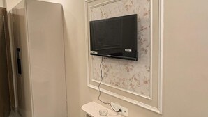 A room with a mounted TV, a white cabinet, and a tiled floor.