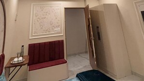 A hotel room with a bed, a ceiling fan, recessed lighting, a wall-mounted air conditioner, and a door leading to another room.