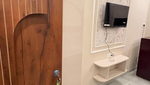 A room with a wooden door, a mounted TV, and a tiled floor.
