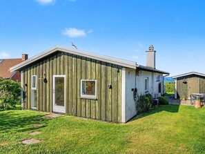 A two-story wooden building with a small attached garage, a visible chimney, and a door leading to a covered porch. - "Edla" - 35m from the sea by Interhome (Frørup)
