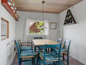 A dining area with a wooden table and chairs, a window with a view of a brick building, a ceiling fan, and a wall-mounted shelf with items. - "Edla" - 35m from the sea by Interhome (Frørup)