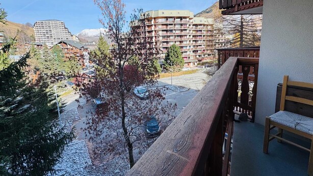 Een balkon met uitzicht op een skigebied, met gebouwen en bomen.
