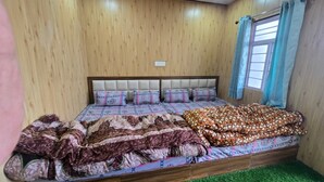 Una cama con ropa de cama estampada, cabecero y ventana con cortinas.