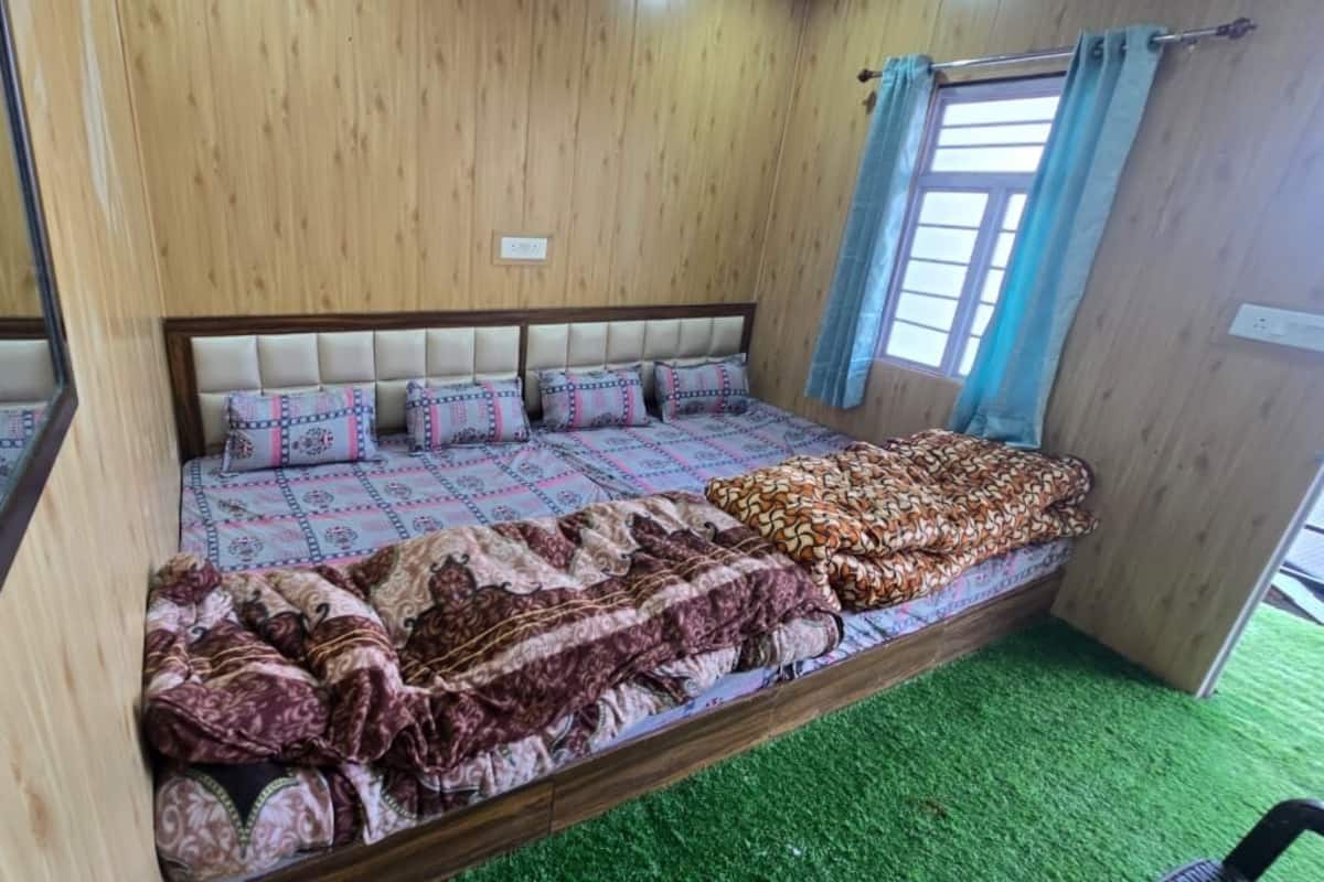 Quarto com cama, espelho, janela com cortinas e tapete verde.