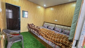 Una habitación con cama, una silla, una puerta y un ventanal pequeño.