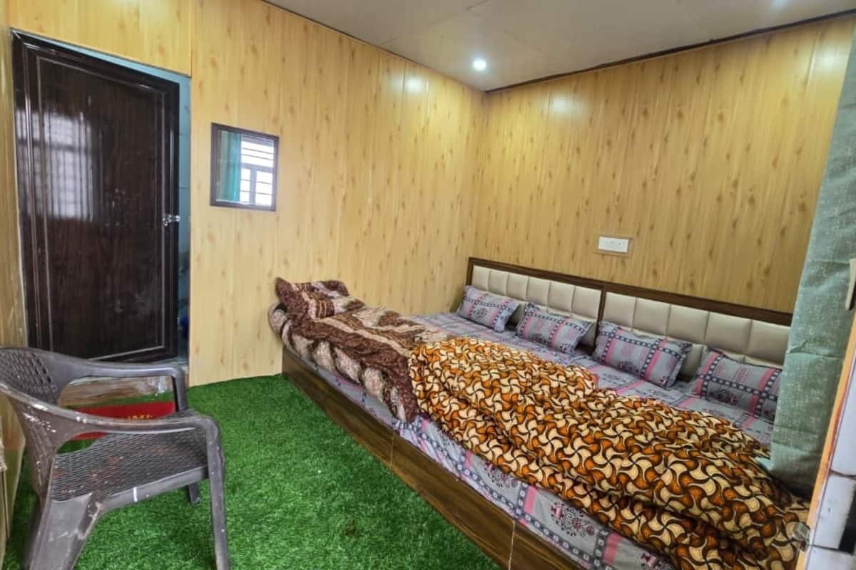 Quarto com uma cama, uma cadeira, uma porta e uma pequena janela.