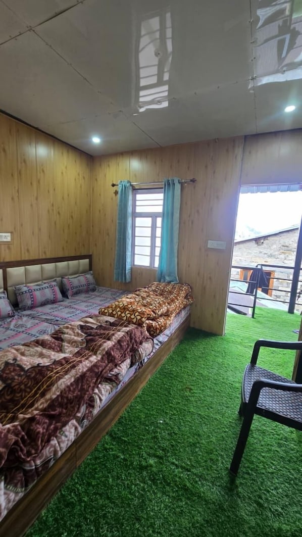 A room with a bed, a window with curtains, and a view of the outside. - Triple S Residency (Kedarnath)