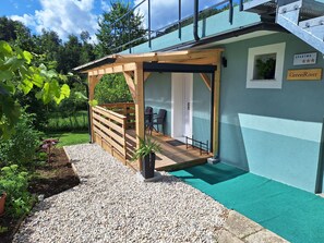 En pergola av trä med en sittplats, en krukväxt och en skylt med texten ”GreenRiver”.