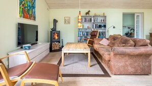 A living room with a television, a fireplace, a bookshelf, a sofa, and a coffee table. - "Amina" - 500m from the sea by Interhome (Egå)