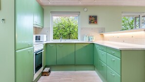A kitchen with green cabinets, a microwave, a toaster, and a window with a view of trees. - "Amina" - 500m from the sea by Interhome (Egå)