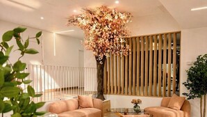 Un interior moderno con un gran árbol como elemento central, asientos acolchados y suelo de madera.