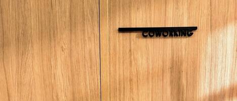 Une porte en bois avec une poignée noire et une pancarte indiquant « ESPACE DE COWORKING ».