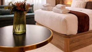 Una habitación de hotel moderna con cama, una mesa redonda, un sofá y un cuadro abstracto grande en la pared.