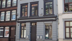 Ein mehrgeschossiges Gebäude mit einem zentralen Eingang, großen Fenstern und einer Ziegel-Fassade.