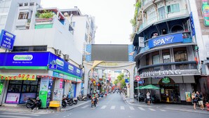 Rua com diversos estabelecimentos, incluindo uma farmácia e um restaurante.