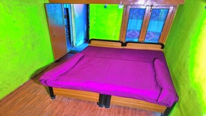 Una habitación pequeña con cama, piso de madera y paredes verdes.